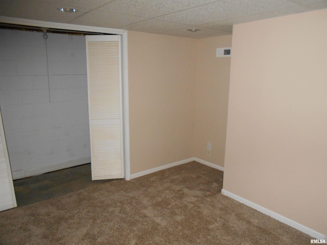 unfurnished bedroom with a closet, a drop ceiling, and dark colored carpet