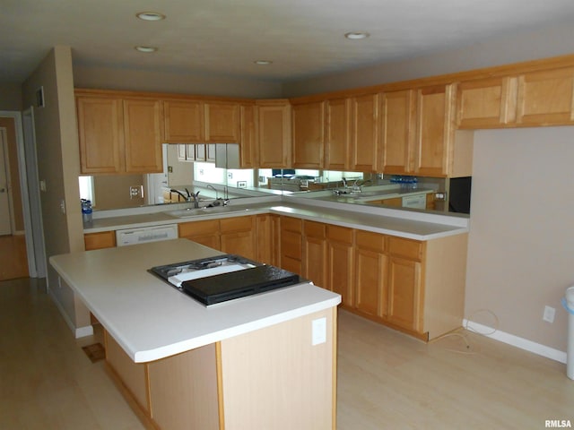 kitchen featuring white dishwasher, light wood-type flooring, sink, and a center island