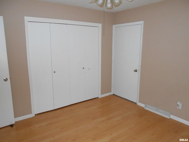 unfurnished bedroom with wood-type flooring, a closet, and ceiling fan