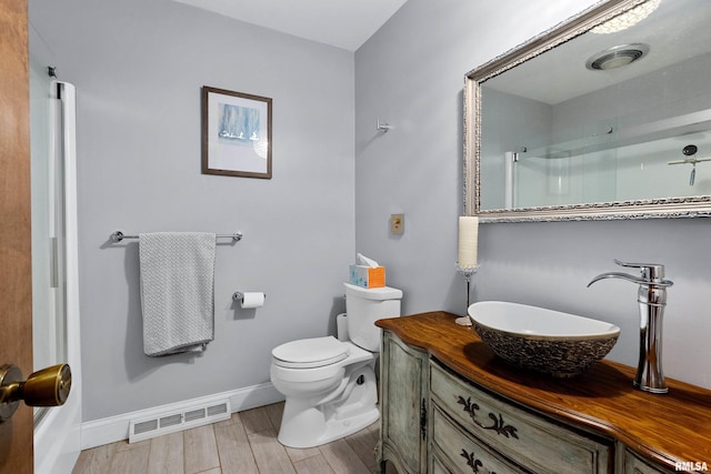 bathroom featuring a shower with shower door, vanity, toilet, and wood-type flooring