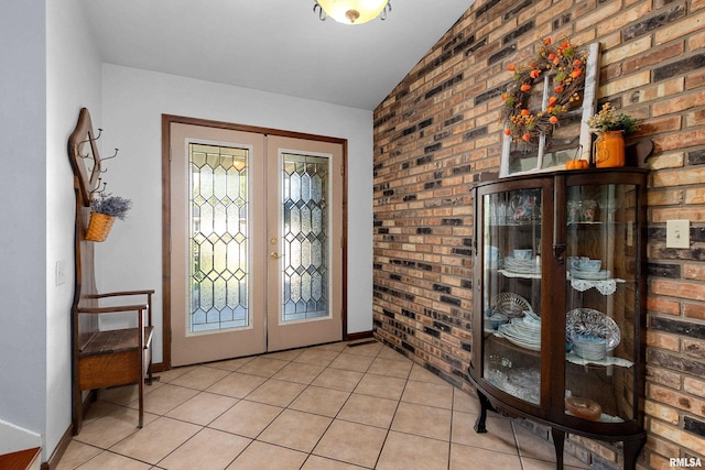 tiled foyer featuring lofted ceiling, french doors, and brick wall