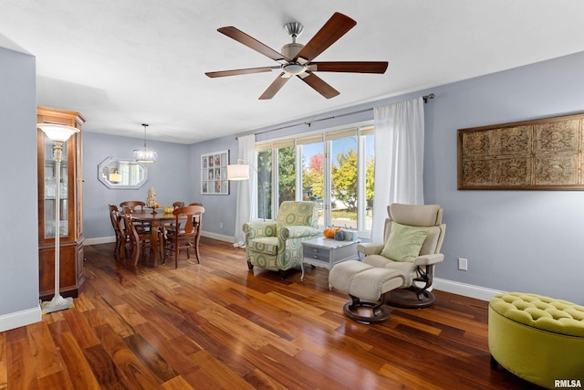 living area with ceiling fan with notable chandelier and dark hardwood / wood-style flooring