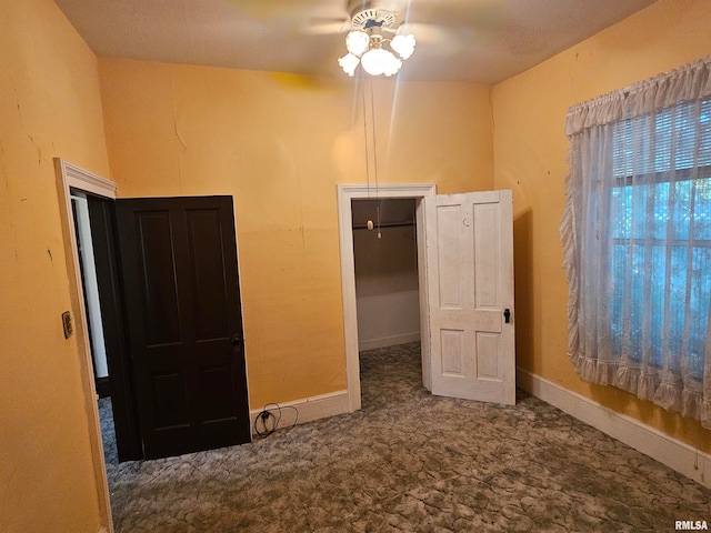 unfurnished bedroom with ceiling fan, a closet, and a walk in closet