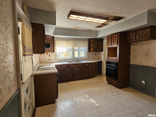 kitchen featuring black oven, dark brown cabinetry, and sink