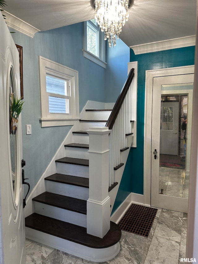 stairway featuring ornamental molding and a chandelier