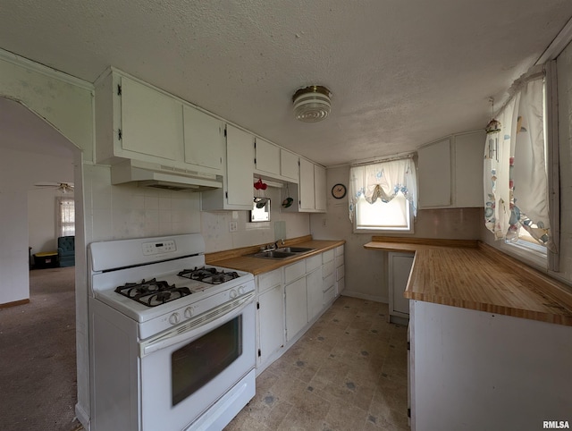 kitchen with white gas range, ceiling fan, sink, a textured ceiling, and white cabinets