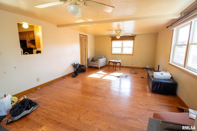 spare room with beam ceiling, light hardwood / wood-style flooring, a textured ceiling, and ceiling fan