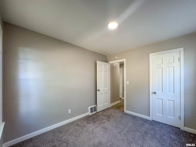 unfurnished bedroom with a closet and dark colored carpet