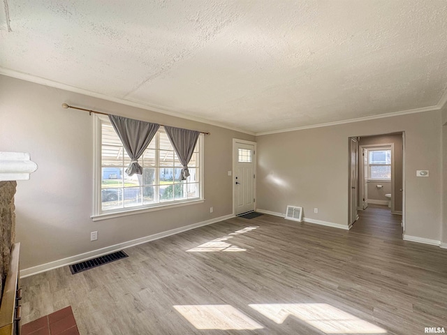 unfurnished living room with a textured ceiling, a healthy amount of sunlight, ornamental molding, and light hardwood / wood-style flooring