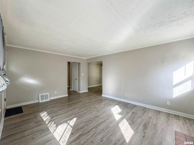 empty room featuring wood-type flooring, ornamental molding, and a textured ceiling