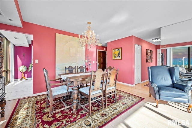 dining space with a notable chandelier and light hardwood / wood-style flooring