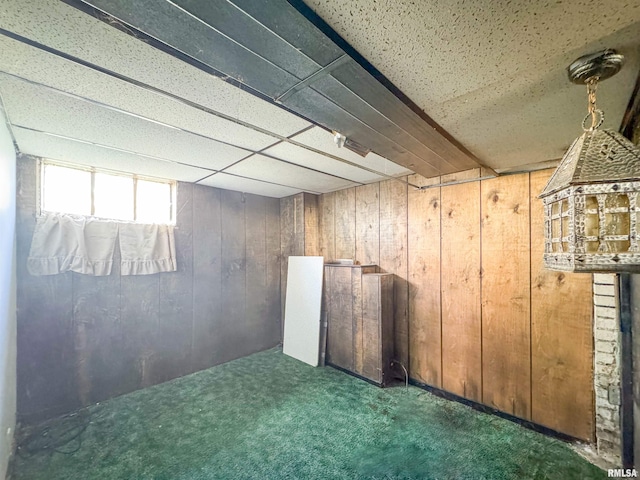 basement featuring wooden walls and dark carpet