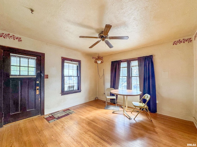 foyer entrance featuring ceiling fan, light hardwood / wood-style flooring, a wealth of natural light, and a textured ceiling