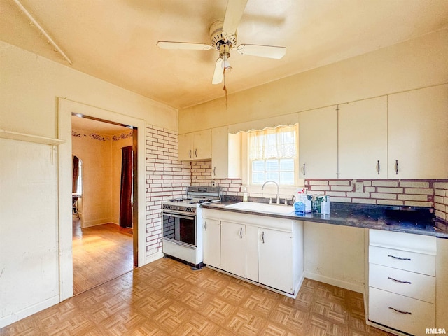 kitchen featuring white range with gas stovetop, sink, and white cabinetry