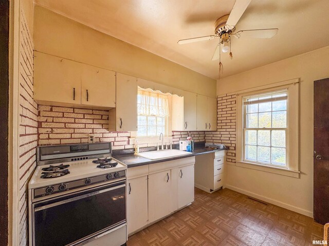782 N Ave B, Canton, IL 61520 - kitchen with white range with gas cooktop, a sink, white cabinetry, a ceiling fan, and backsplash