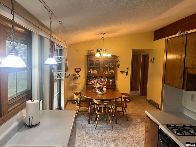 carpeted dining room with a chandelier, a textured ceiling, and lofted ceiling