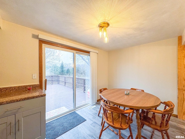 dining area featuring a textured ceiling and light wood-type flooring