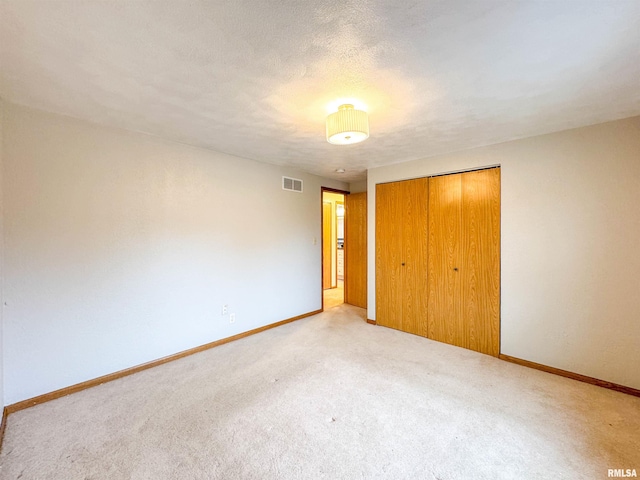 unfurnished bedroom with light carpet, a textured ceiling, and a closet