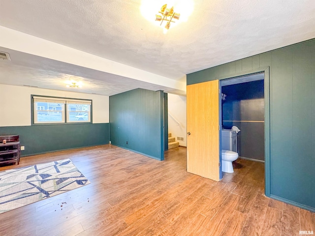 bedroom featuring connected bathroom, wood-type flooring, and a textured ceiling