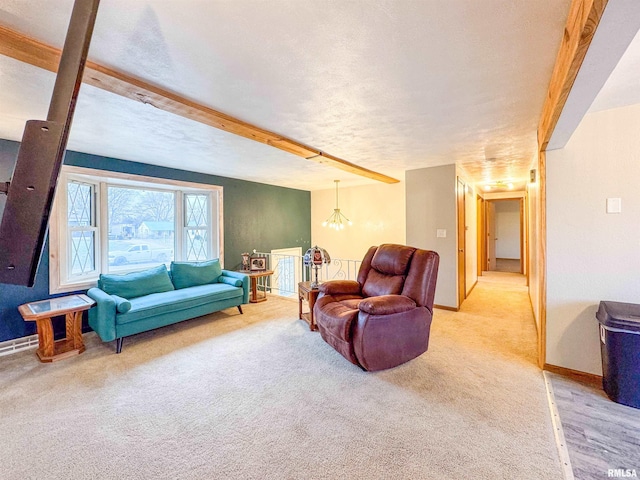 carpeted living room with beam ceiling, a textured ceiling, and an inviting chandelier