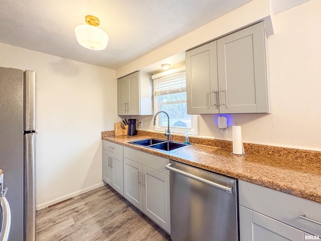 kitchen with gray cabinetry, light hardwood / wood-style flooring, sink, and stainless steel appliances