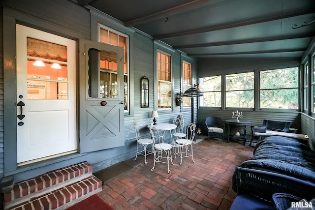 sunroom / solarium featuring vaulted ceiling with beams