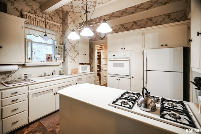 kitchen featuring white appliances, white cabinetry, decorative light fixtures, and sink