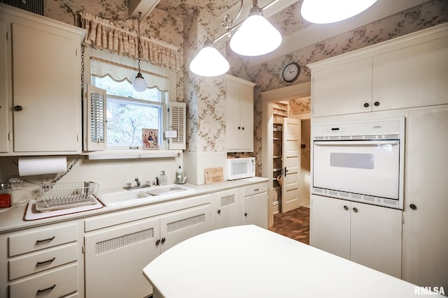 kitchen featuring white cabinets, hanging light fixtures, and white appliances