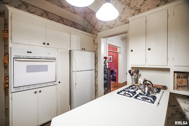 kitchen with white cabinets, dark wood-type flooring, and white appliances