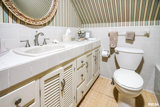 bathroom with tile walls, vanity, and toilet