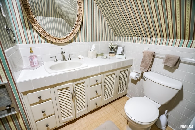 bathroom featuring vanity, toilet, and tile walls