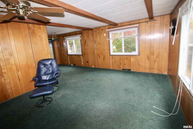 interior space featuring carpet flooring, wood walls, beamed ceiling, and ceiling fan