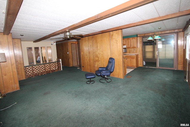 basement featuring wood walls, ceiling fan, and dark carpet