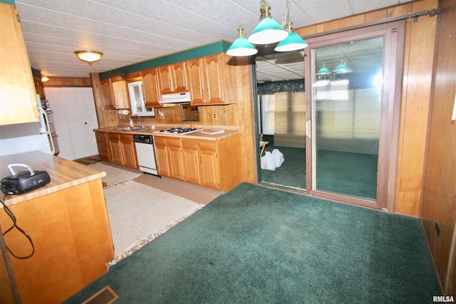 kitchen featuring light colored carpet, dishwasher, wood walls, pendant lighting, and range hood