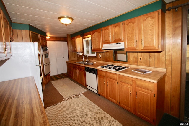 kitchen with sink, white appliances, and wooden walls