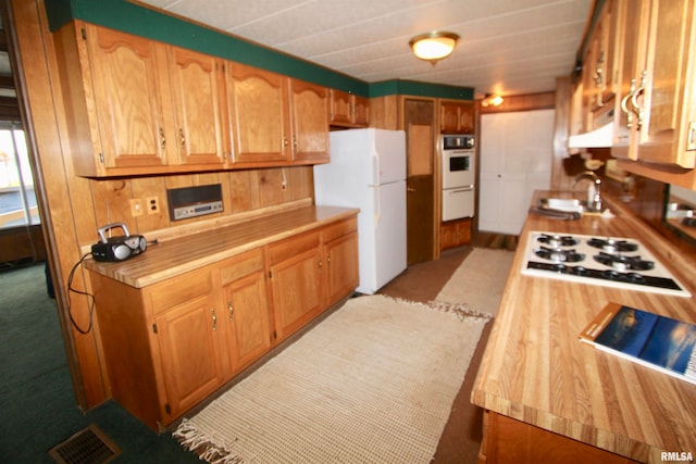 kitchen with ventilation hood, white appliances, sink, and light carpet