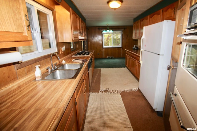 kitchen featuring dark carpet, extractor fan, white refrigerator, gas stovetop, and sink