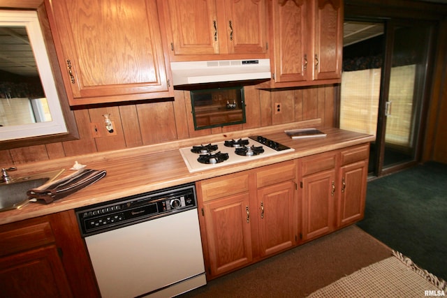 kitchen featuring wood walls, white appliances, and dark colored carpet