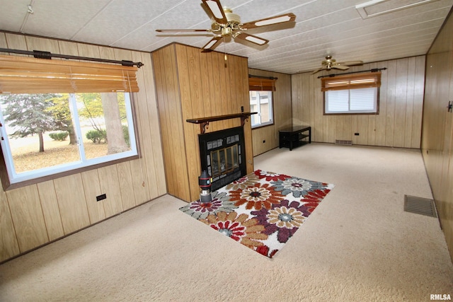 living room featuring wood walls, light colored carpet, and a healthy amount of sunlight