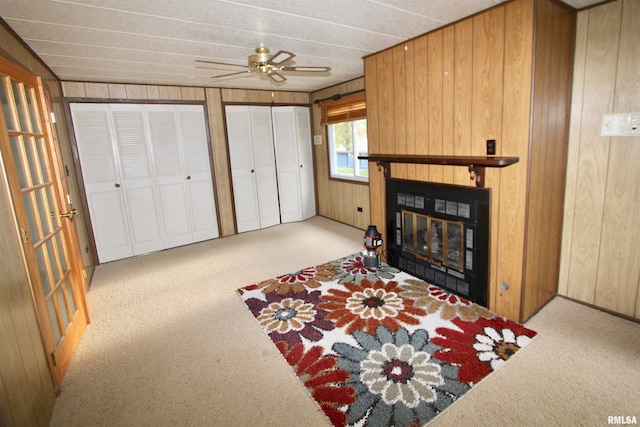 carpeted living room with ceiling fan and wooden walls