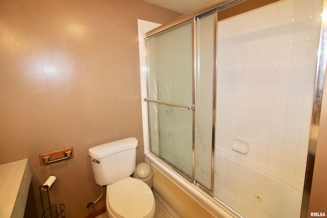 bathroom featuring toilet and bath / shower combo with glass door