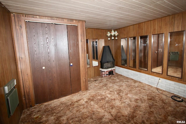 interior space with carpet flooring, wood walls, a chandelier, and a closet