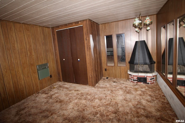 unfurnished bedroom featuring a chandelier, wooden walls, a closet, and carpet