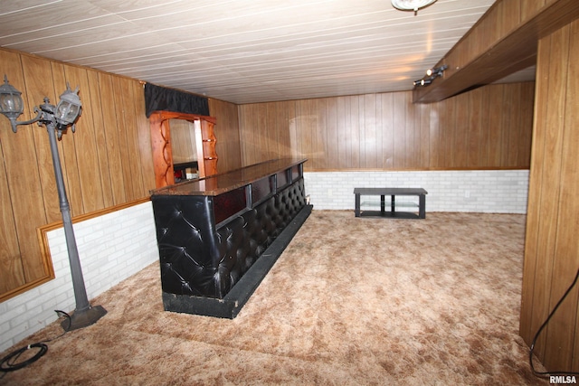 bar featuring wooden walls, light carpet, and brick wall