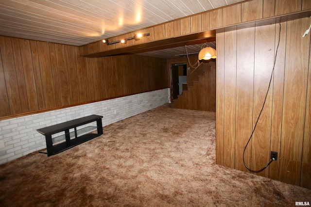 basement featuring wood walls, carpet flooring, and brick wall