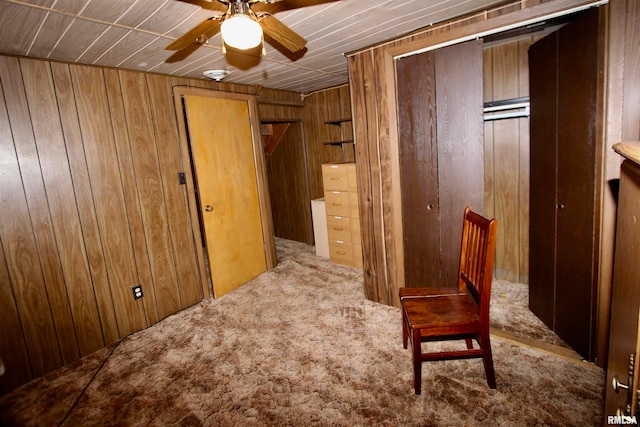 sitting room featuring carpet flooring, wooden walls, and ceiling fan