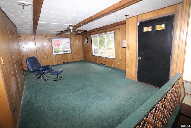 unfurnished room with wooden walls, beam ceiling, and dark carpet