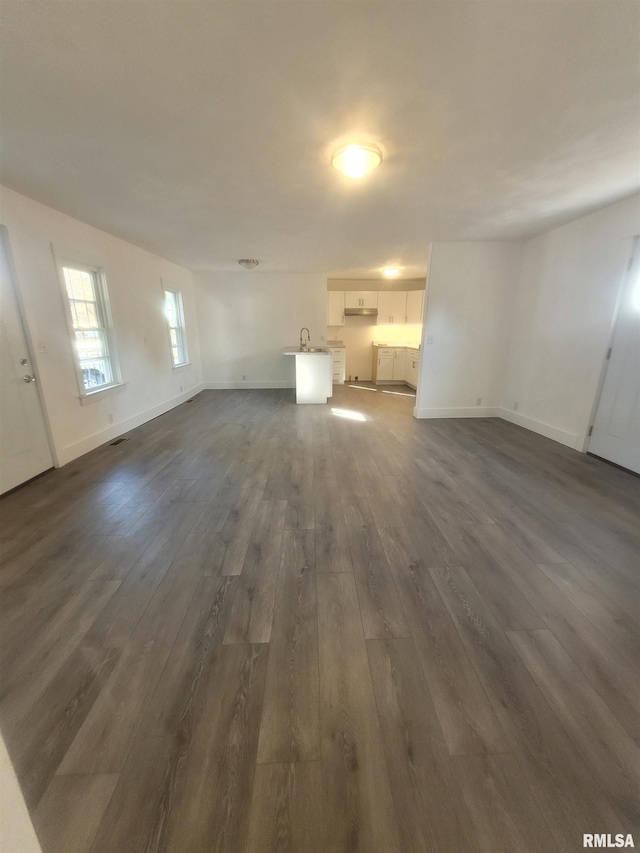 unfurnished living room featuring sink and dark hardwood / wood-style flooring