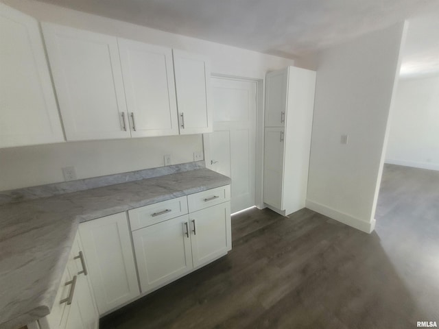 kitchen with white cabinetry, light stone countertops, and dark hardwood / wood-style floors