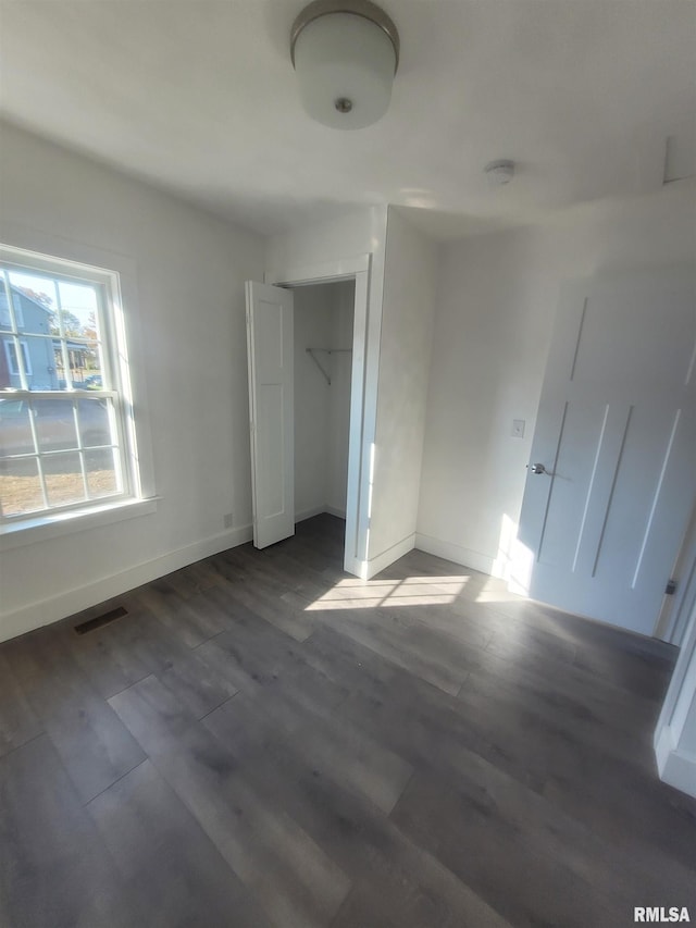 unfurnished bedroom with a closet and dark wood-type flooring